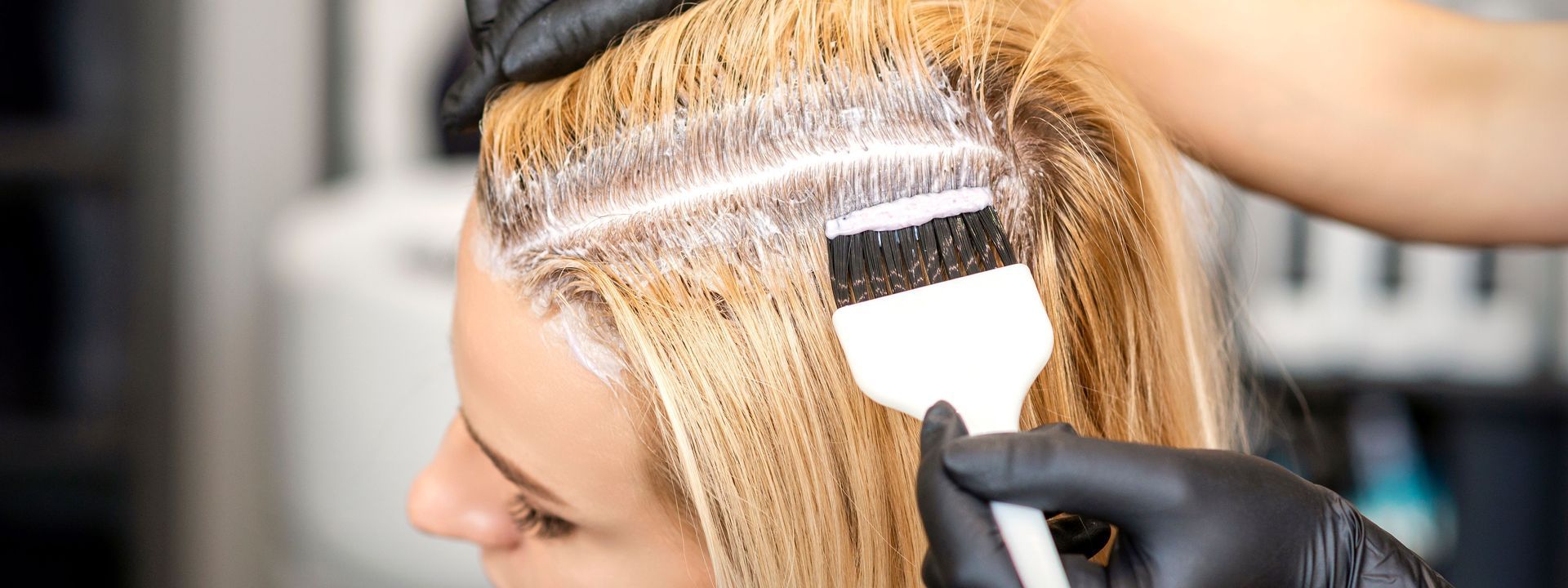 Coiffeuse appliquant une coloration blonde au pinceau et avec du papier aluminium sur les cheveux d’une femme