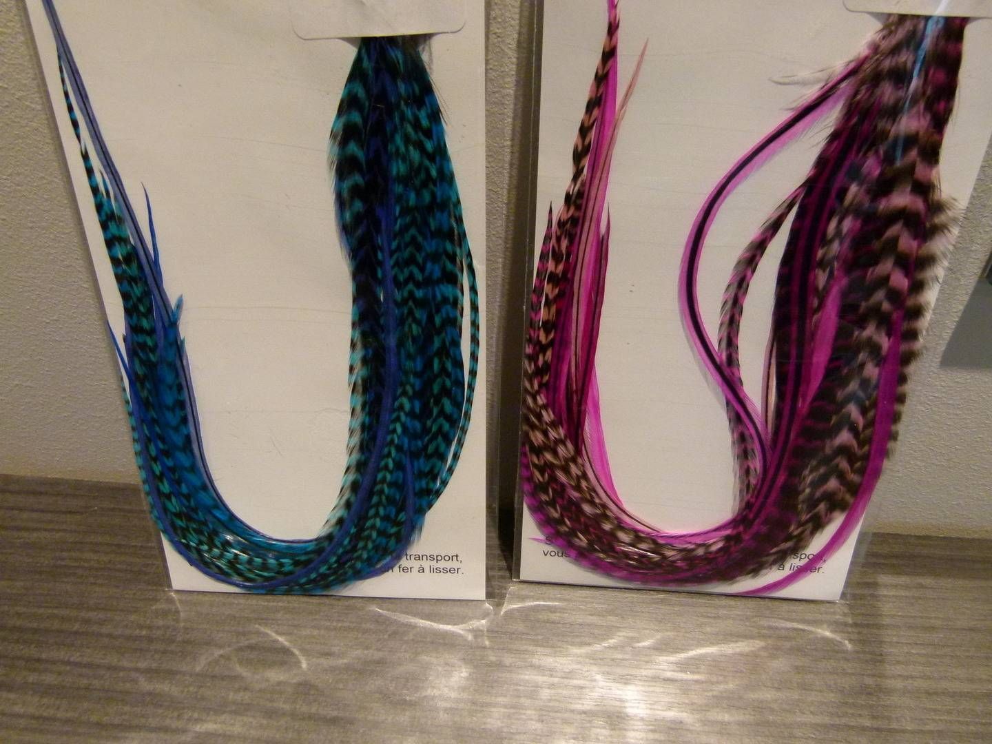 Deux extensions de cheveux fantaisie tressées et colorées, bleu, turquoise, rose et noir, présentées dans des boîtes.