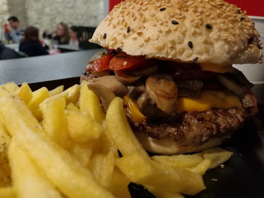 Um close de um hambúrguer e batatas fritas em uma mesa