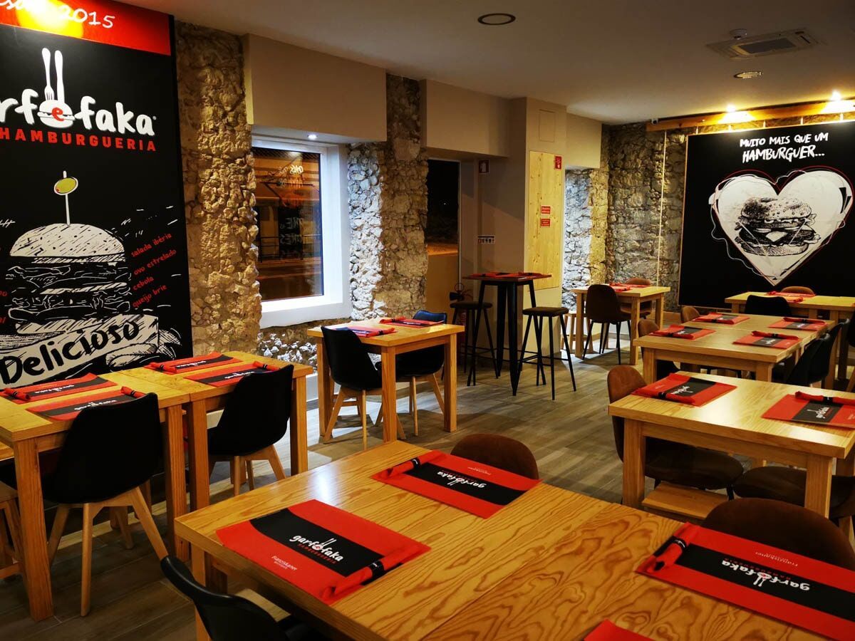 Um restaurante com mesas e cadeiras e uma placa que diz delicioso