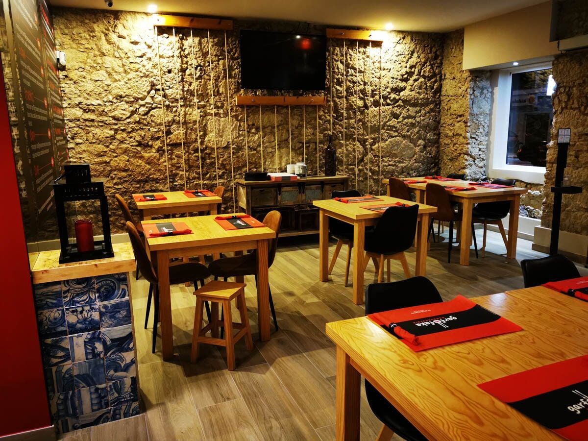 Um restaurante com mesas e cadeiras de madeira e uma parede de pedra