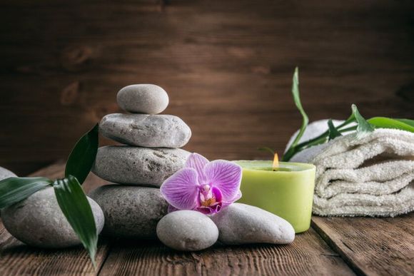Piedras apiladas, orquídea, vela encendidamadera, para una escena similar a un spa.