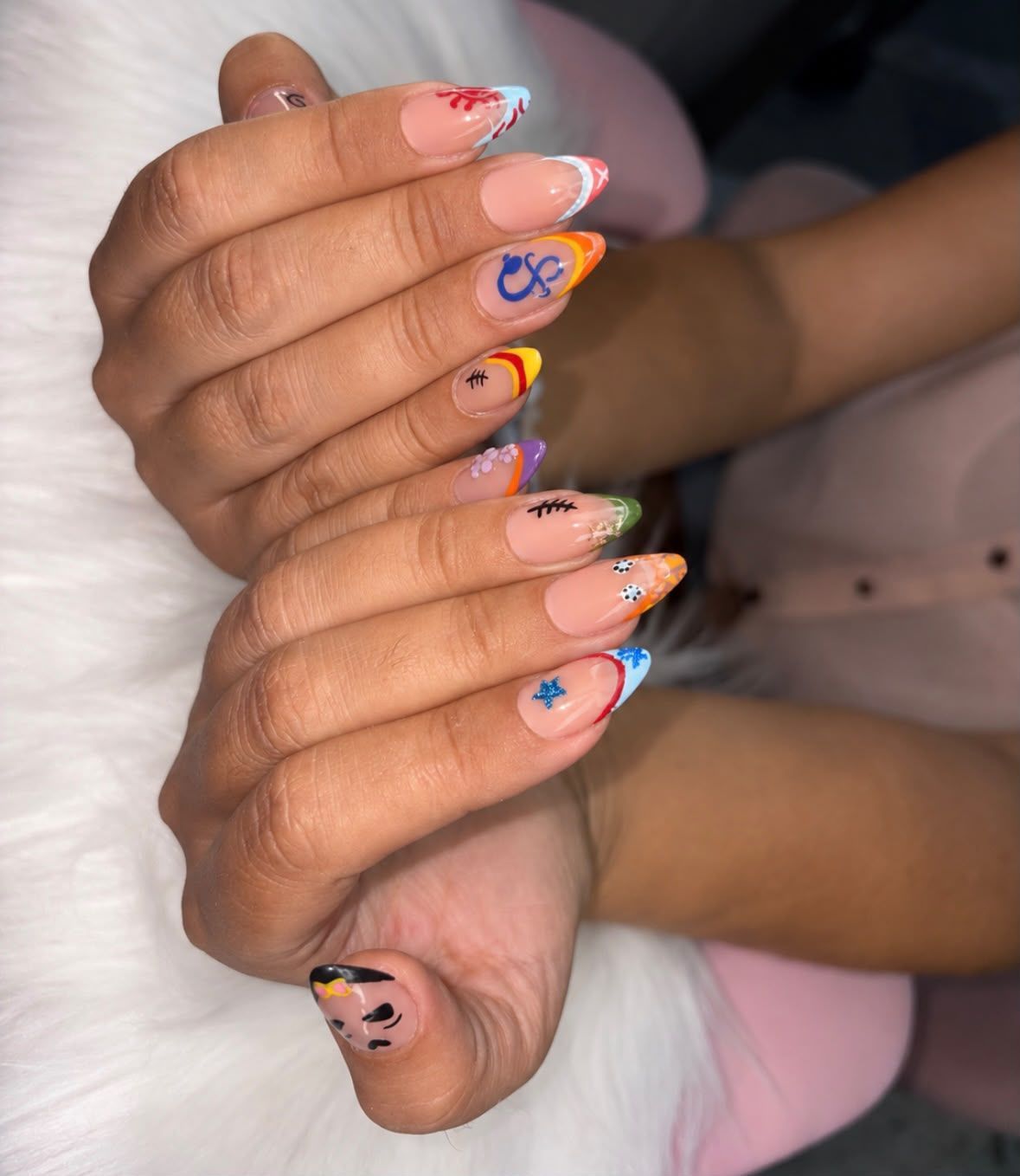 Manos con uñas decoradas con coloridos diseños, entrelazadas sobre un fondo claro.
