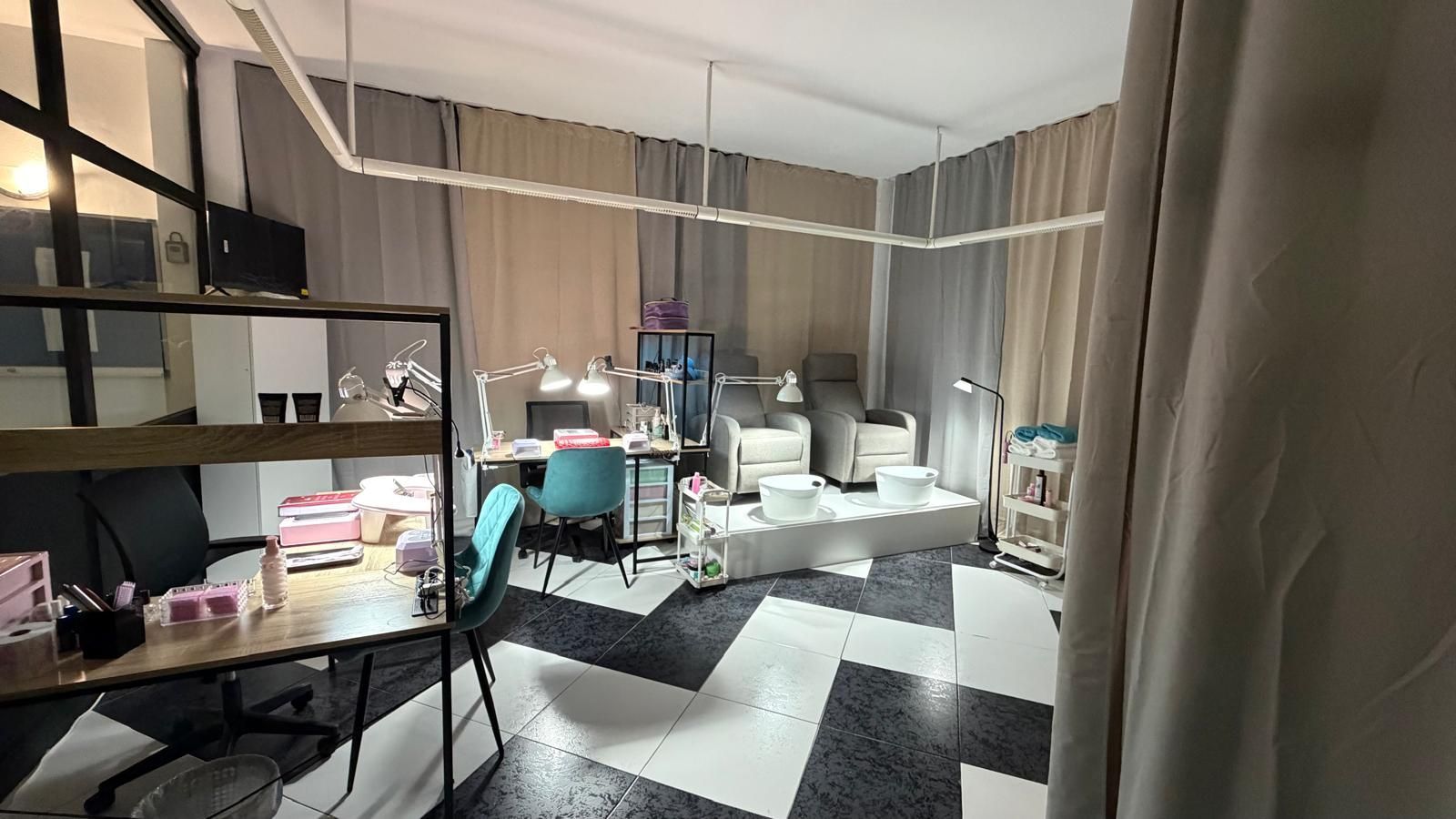 Habitación pequeña y desordenada con estanterías, botellas y una cama o sofá junto a una alfombra con estampado de zigzag en blanco y negro.