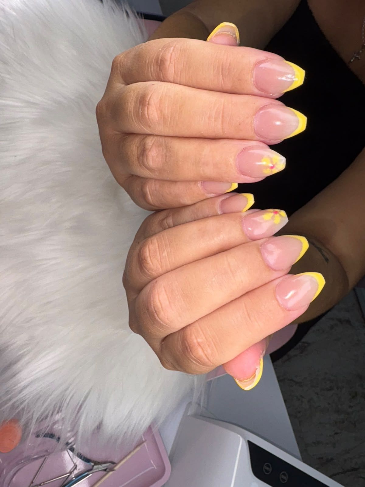 Manos con uñas largas de color rosa y puntas amarillas sosteniendo un objeto blanco y esponjoso.