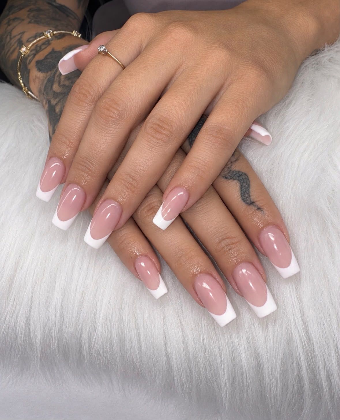 Manos con manicura francesa rosa brillante descansando sobre una superficie de piel blanca.