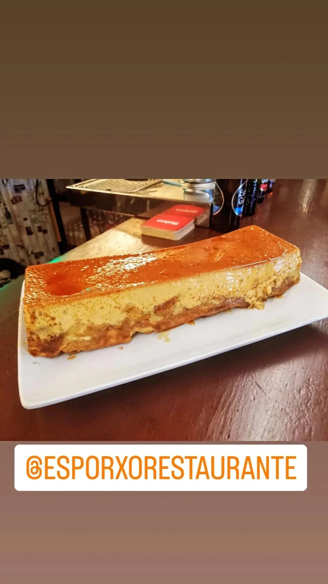 Un pastel rectangular en un plato blanco, en un restaurante. Glaseado de naranja.