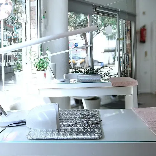Un escritorio con una lámpara y un teclado en una habitación con muchas ventanas.