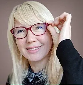 Una mujer que lleva gafas sonríe y se ajusta las gafas.