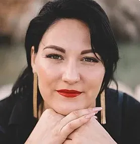 Un primer plano de una mujer que lleva pendientes y lápiz labial rojo.