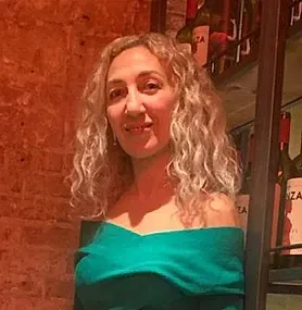 Una mujer con un vestido verde está parada frente a un estante de vinos.