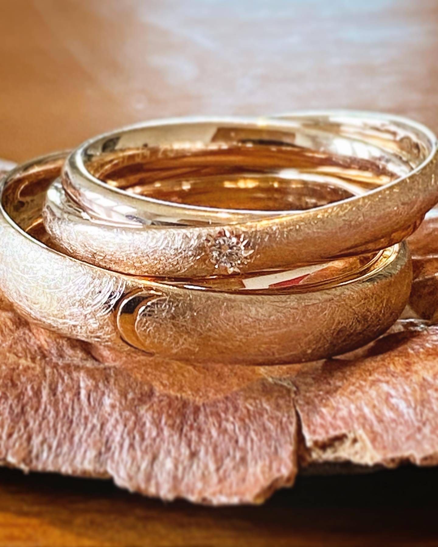 Goldene Armreifen lagen gestapelt auf einer strukturierten, braunen Oberfläche.