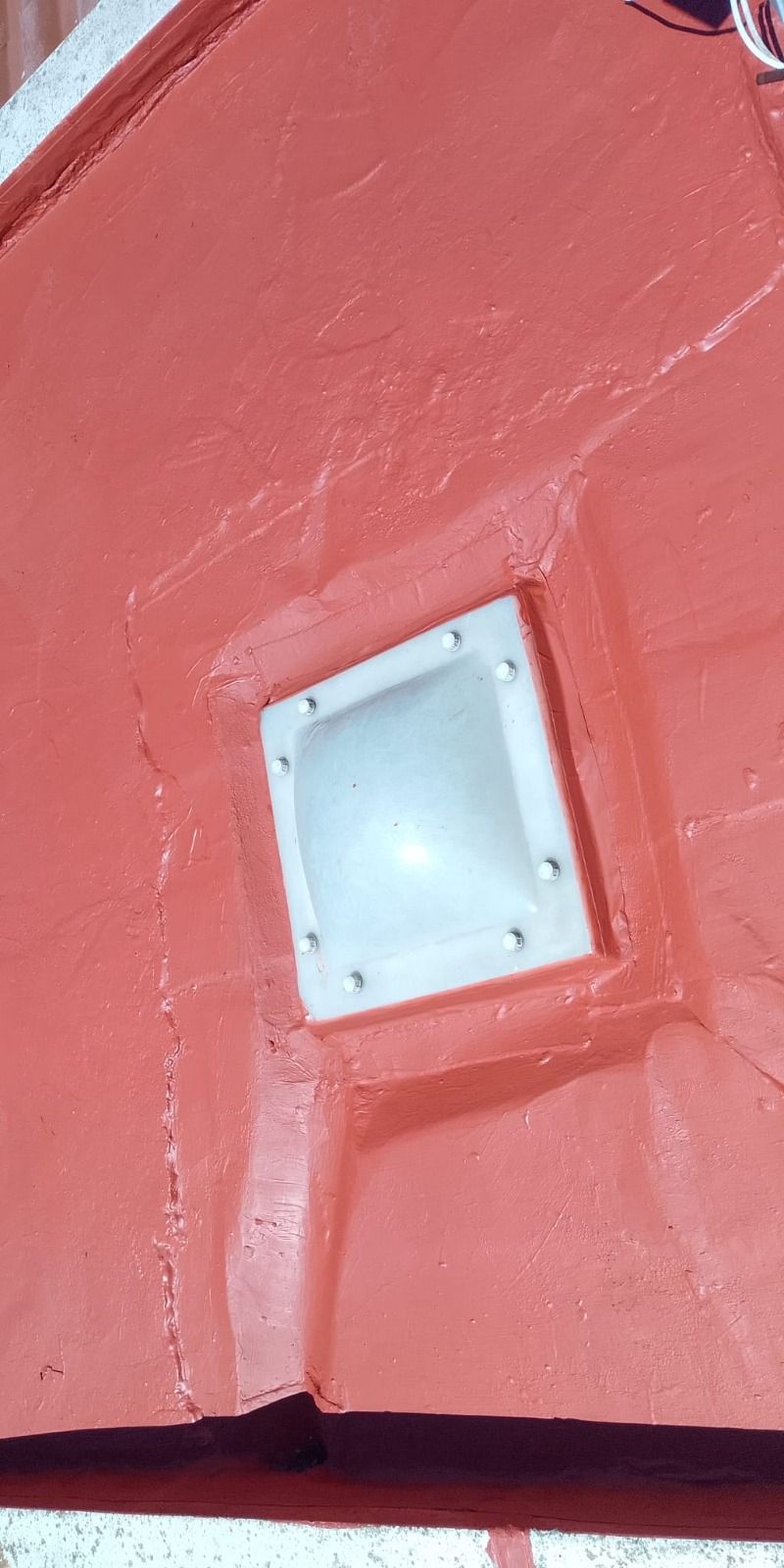 Lámpara pequeña cuadrada de color blanco montada sobre una pared roja texturizada.