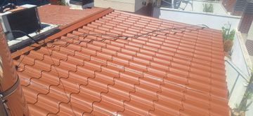 Azotea con hileras de tejas de arcilla roja y una pequeña estructura negra cerca de la parte superior izquierda.