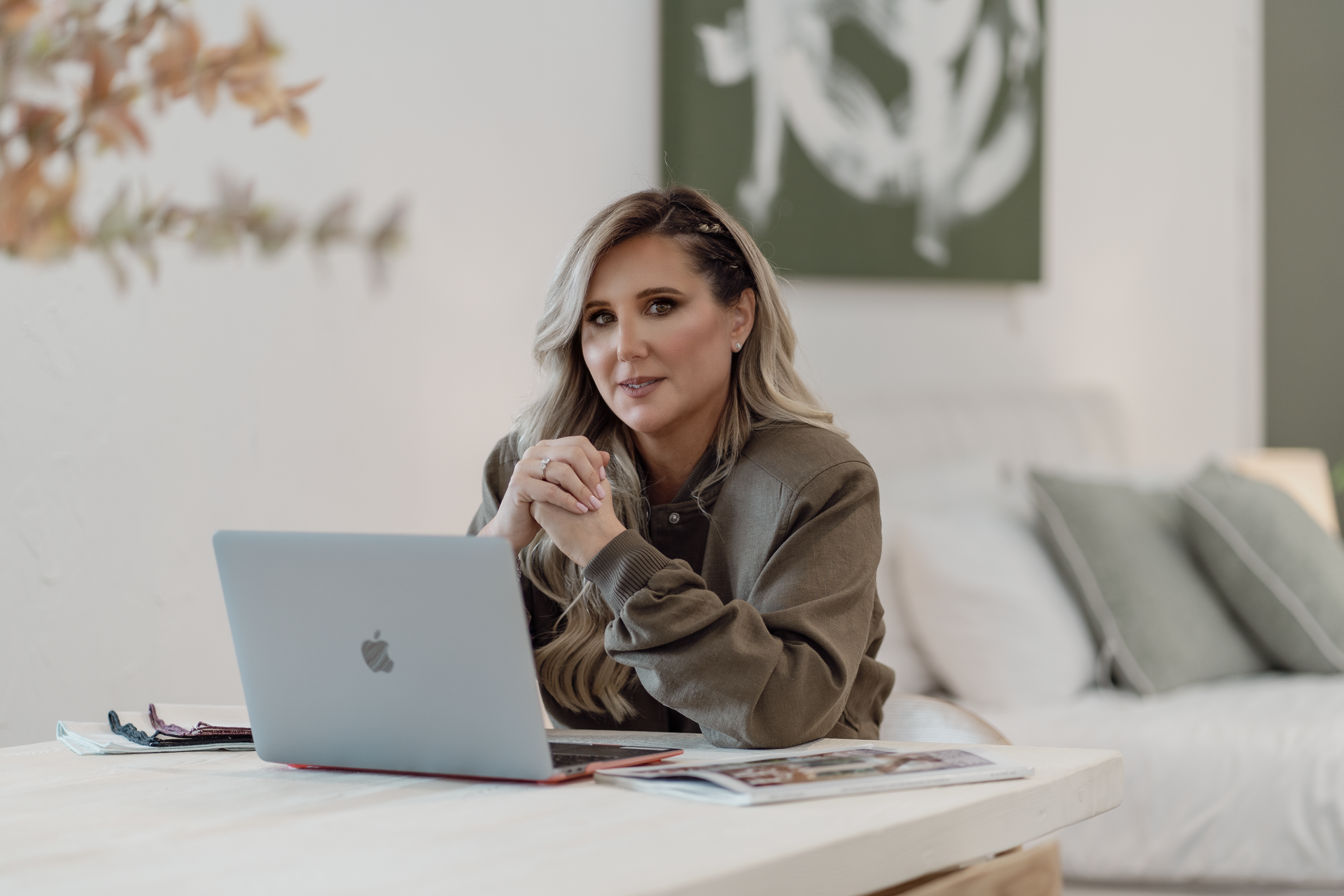 Woman at a desk using a laptop in a bright, modern bedroom or home office