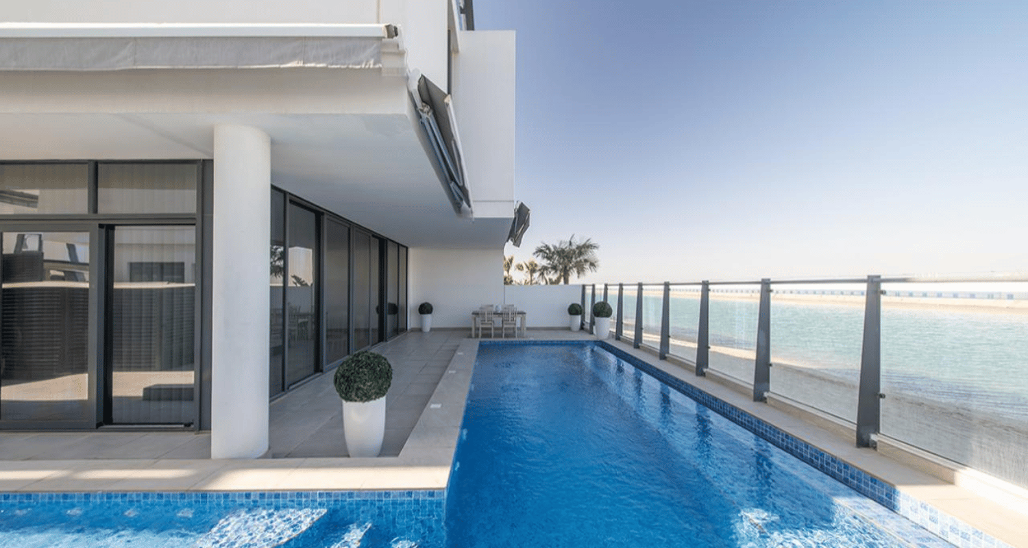 Modern rooftop infinity pool beside a glass railing overlooking the ocean