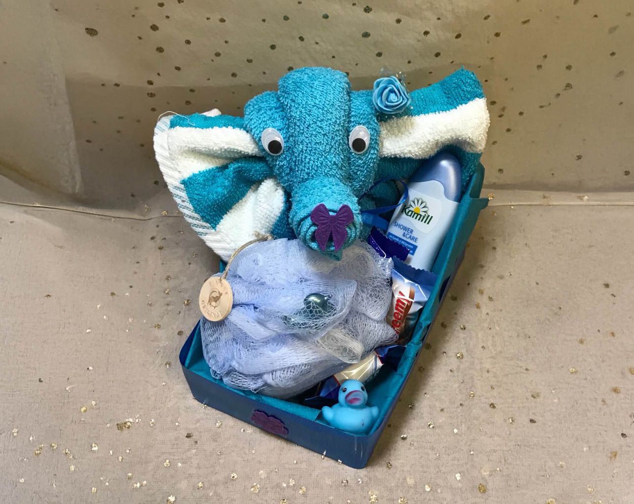 Ein Baby-Geschenkkorb mit einem Handtuchtier, einem blauen Waschlappen und Toilettenartikeln.