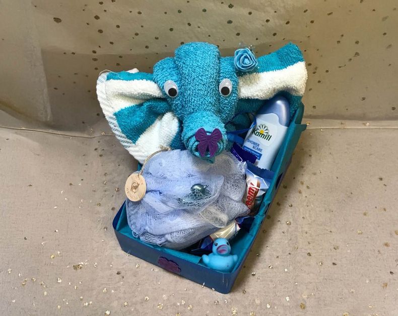 Ein Baby-Geschenkkorb mit einem Handtuchtier, einem blauen Waschlappen und Toilettenartikeln.