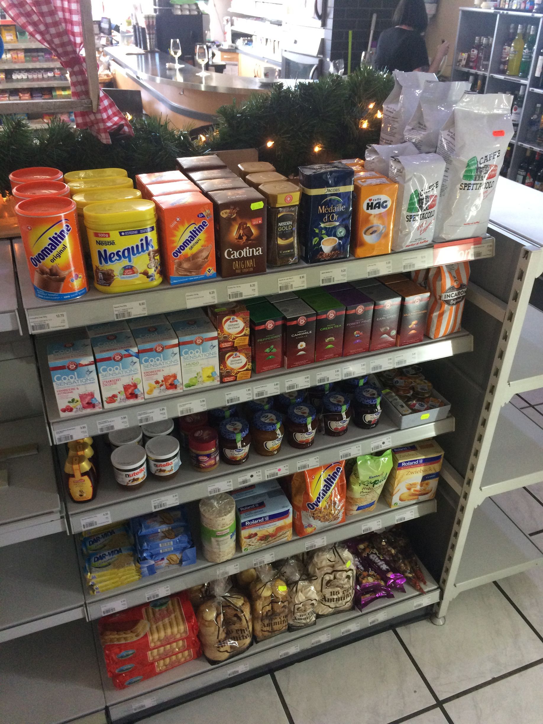 Regal mit Lebensmitteln, darunter Kaffee, Kekse und Nutella, in einem Geschäft.