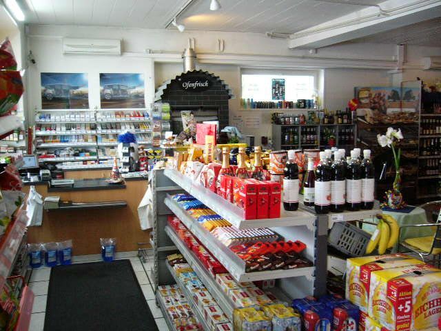 Innenansicht eines kleinen Lebensmittelladens mit verschiedenen Produkten in den Regalen.