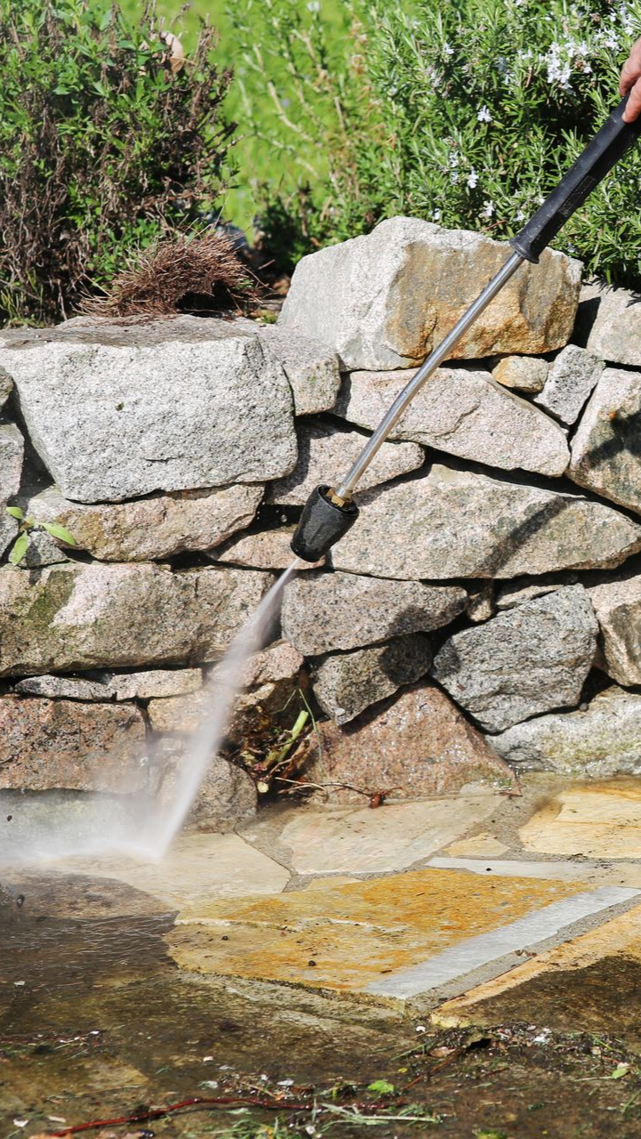 Nettoyage au nettoyeur haute pression d'un mur en pierre et d'un patio.