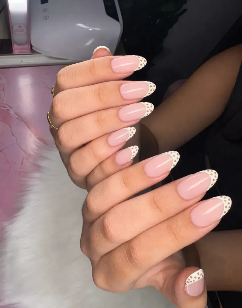 Manos que muestran uñas largas de color rosa pálido con puntas francesas de purpurina blanca.