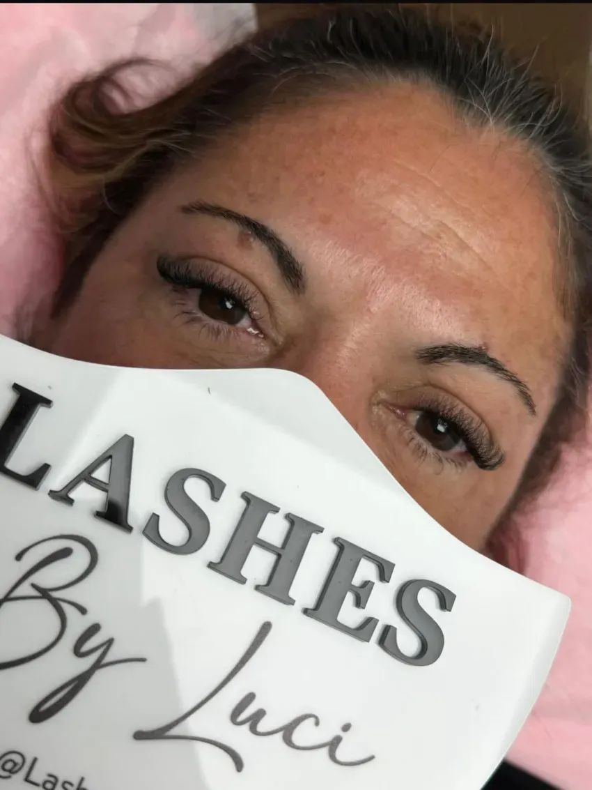 Mujer tumbada con los ojos cerrados, sosteniendo un cartel que dice