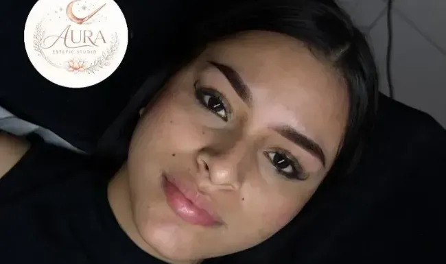 Primer plano de una mujer descansando con una suave sonrisa, con el logotipo circular de AURA en la esquina.