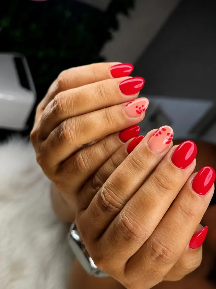 Manos con uñas pintadas de color rojo brillante, juntas sobre un fondo borroso.