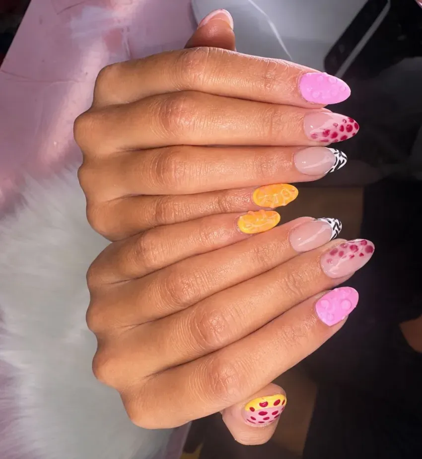 Manos bien cuidadas con largas uñas acrílicas con purpurina de colores y estampado de corazones, exhibidas juntas.