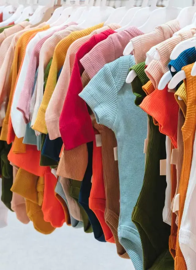 Una fila de camisetas coloridas están colgadas en un estante en una tienda.