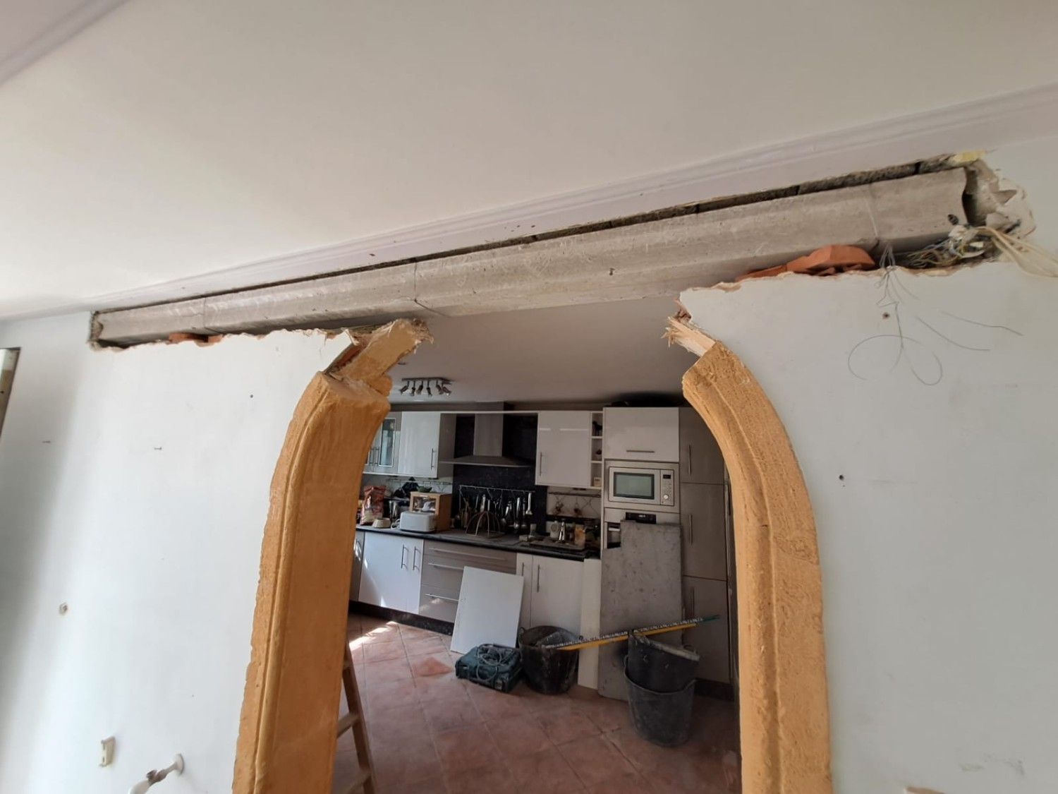 Un trabajador con casco y guantes sostiene una placa de yeso dentro de una habitación en renovación.