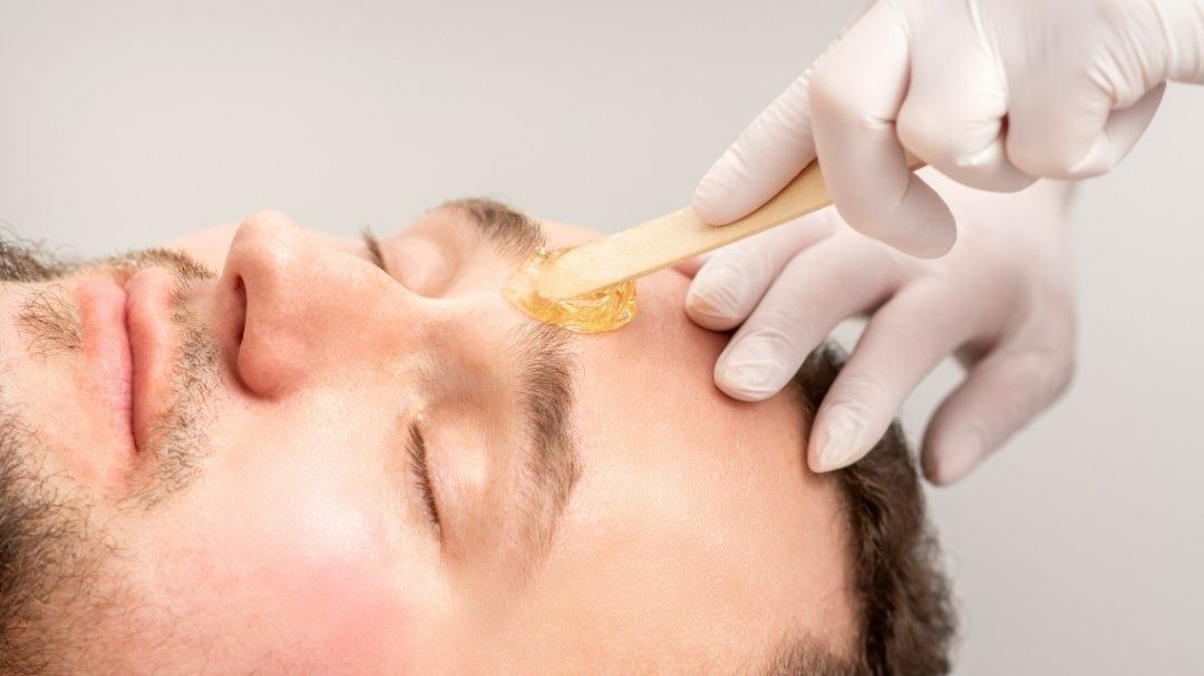 Un hombre se está depilando las cejas en un salón de belleza.