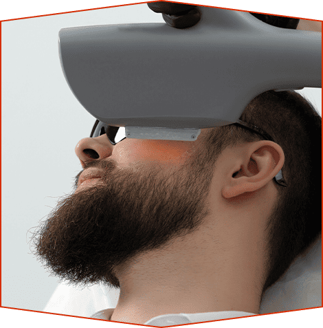 Una persona recibe un tratamiento facial basado en luz con un dispositivo manual colocado cerca de su mejilla.