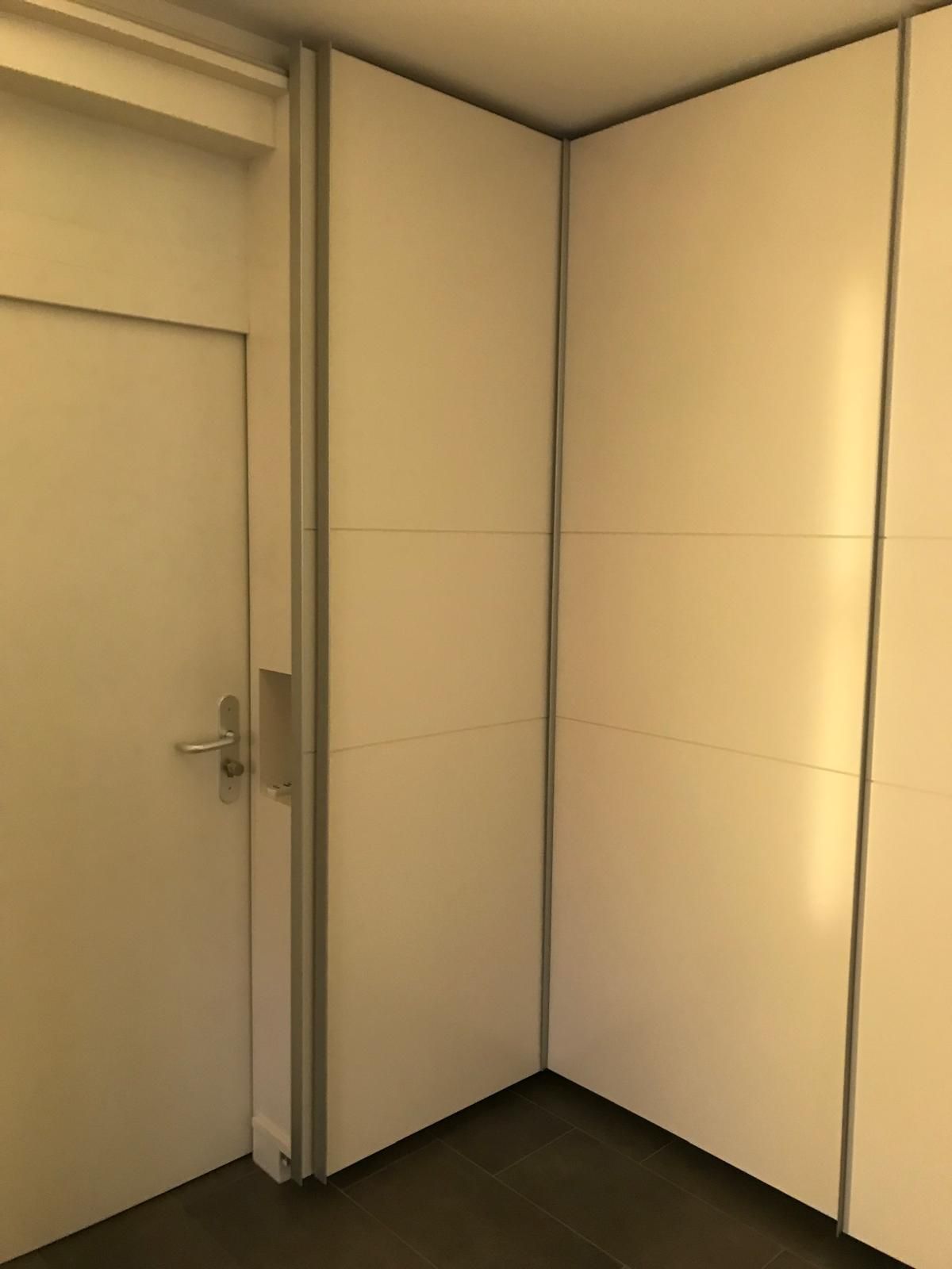 Eine Zimmerecke mit weißen Wänden und einer Tür