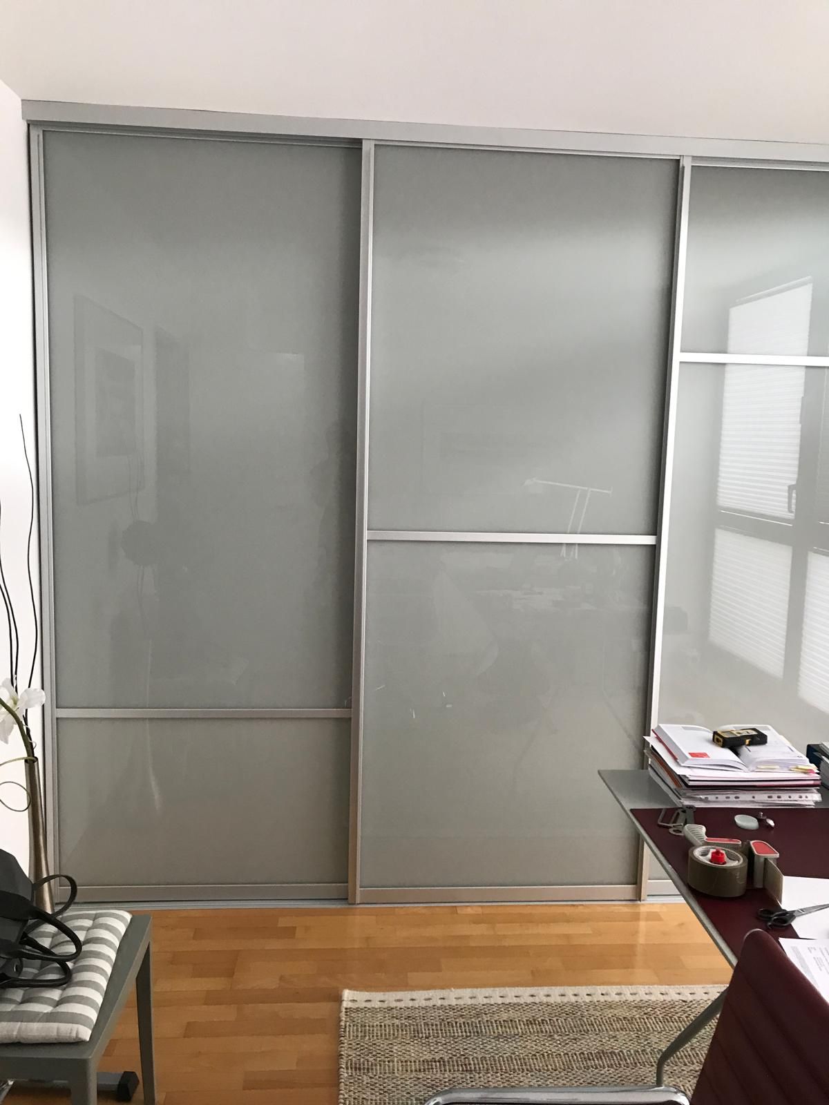 Ein Zimmer mit Glasschiebetüren und einem Schreibtisch.