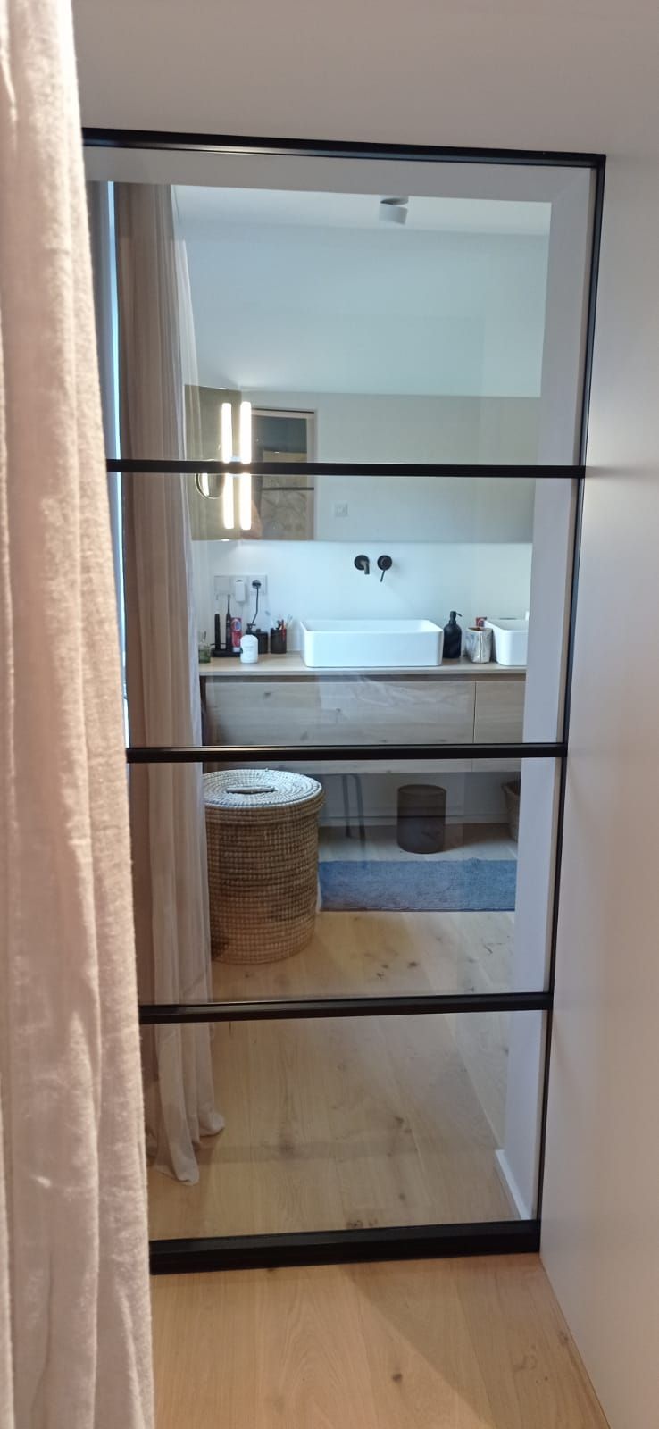 Ein Badezimmer, das durch eine Glasschiebetür zu erreichen ist.