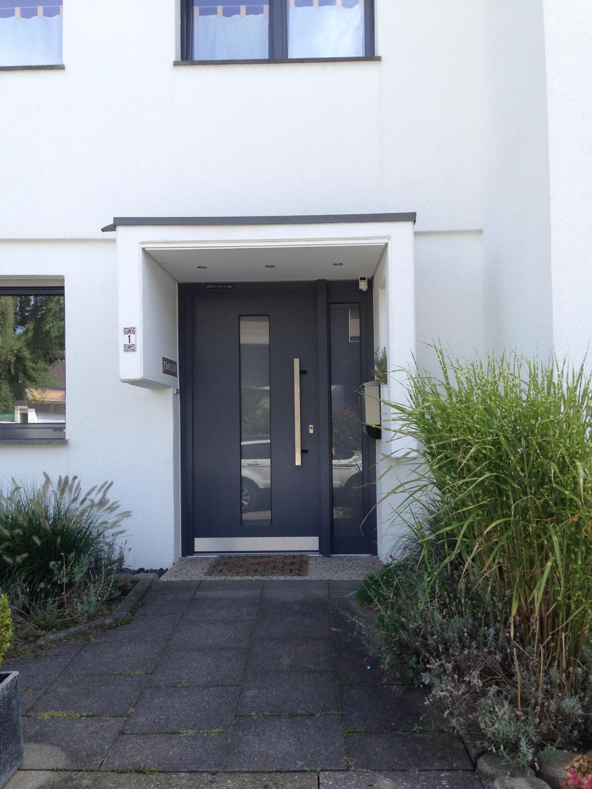 Die Eingangstür eines weißen Hauses mit einer schwarzen Tür