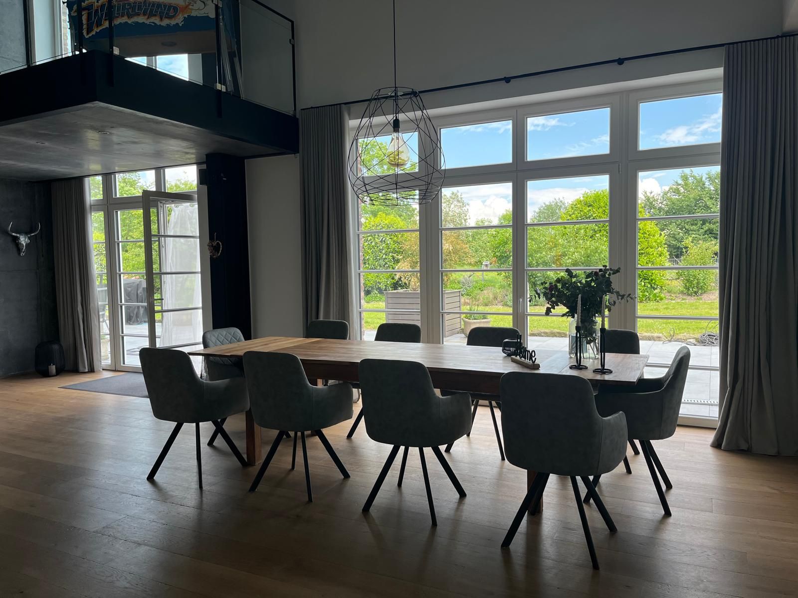 Ein großes Esszimmer mit Tisch und Stühlen und vielen Fenstern.