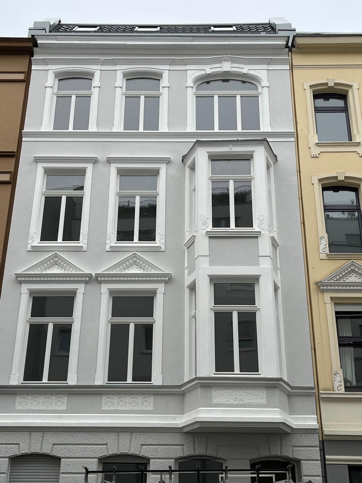 Ein großes Gebäude mit vielen Fenstern ist von anderen Gebäuden umgeben.