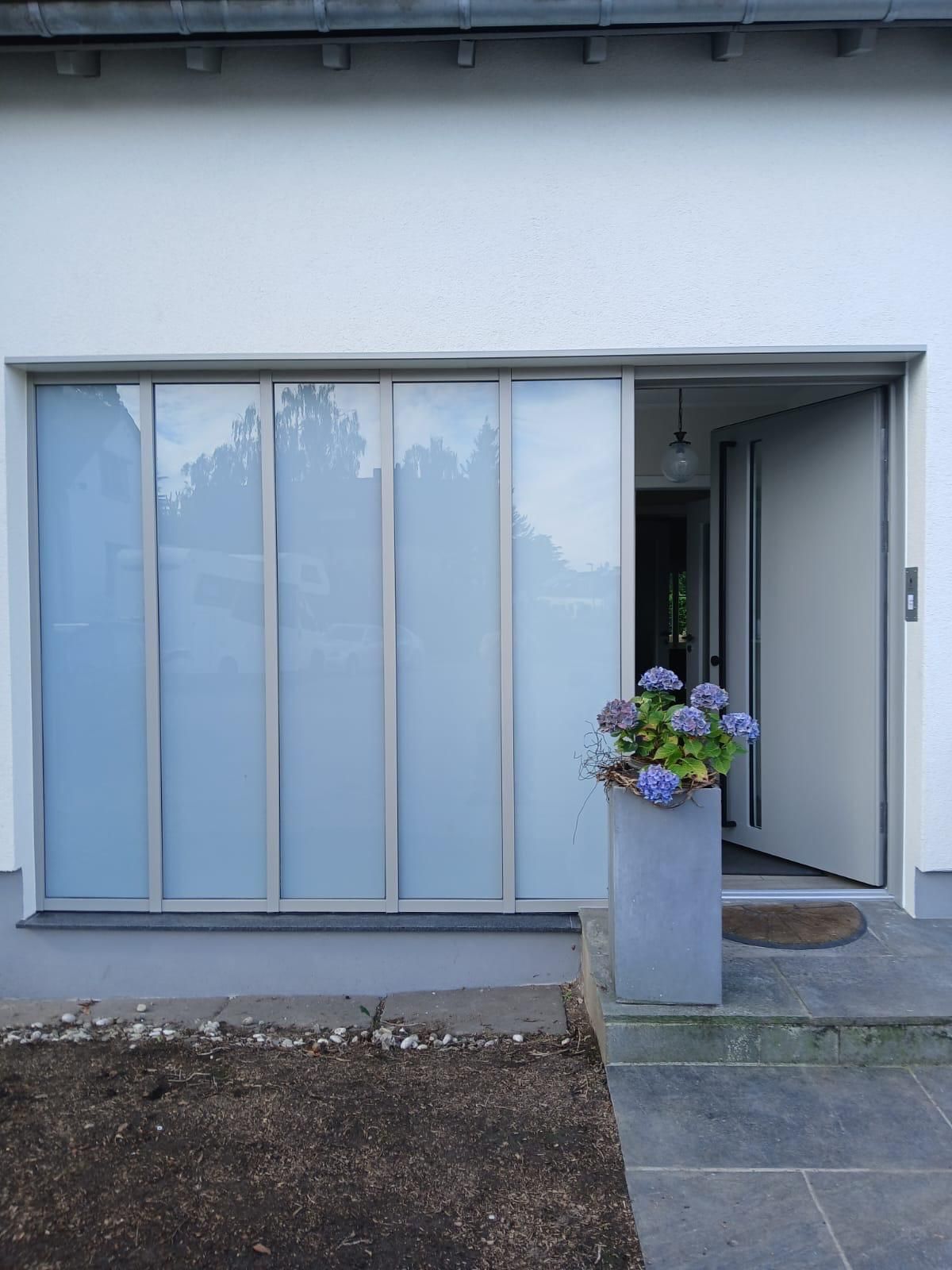 Ein Blumentopf mit lila Blumen steht vor einer Glasschiebetür