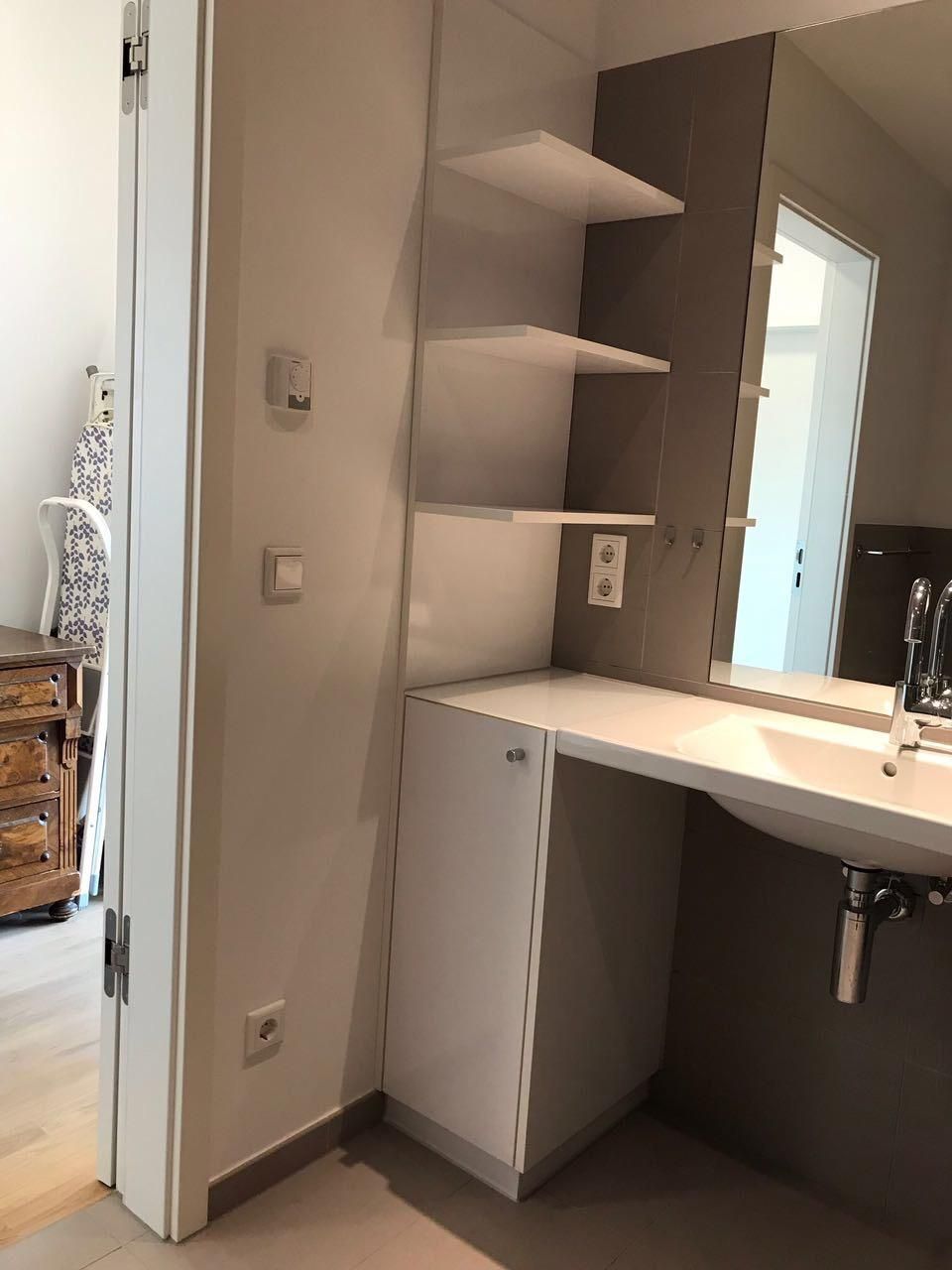 Ein Badezimmer mit Waschbecken, Spiegel und Regalen