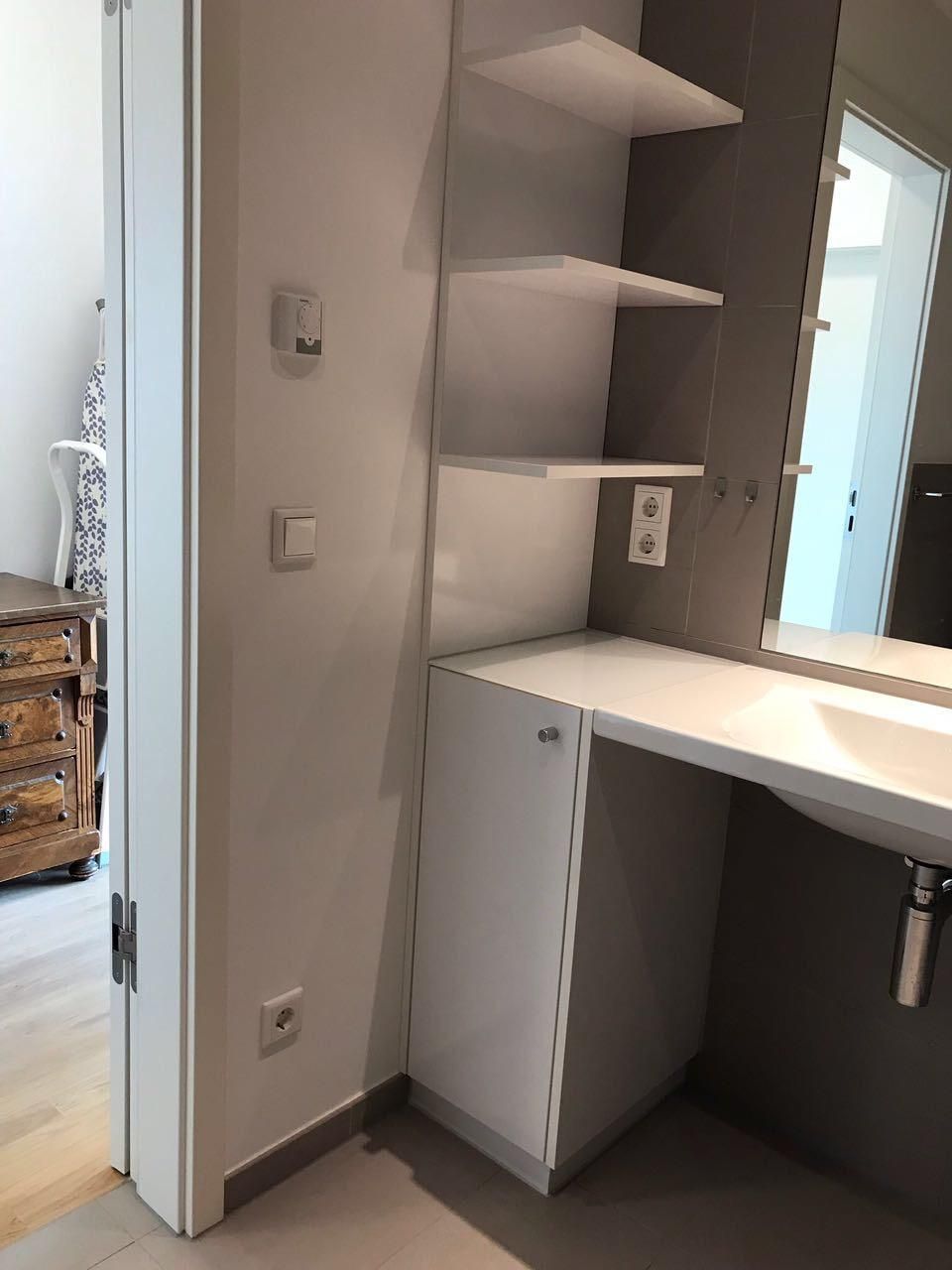 Ein Badezimmer mit Waschbecken, Spiegel und Regalen