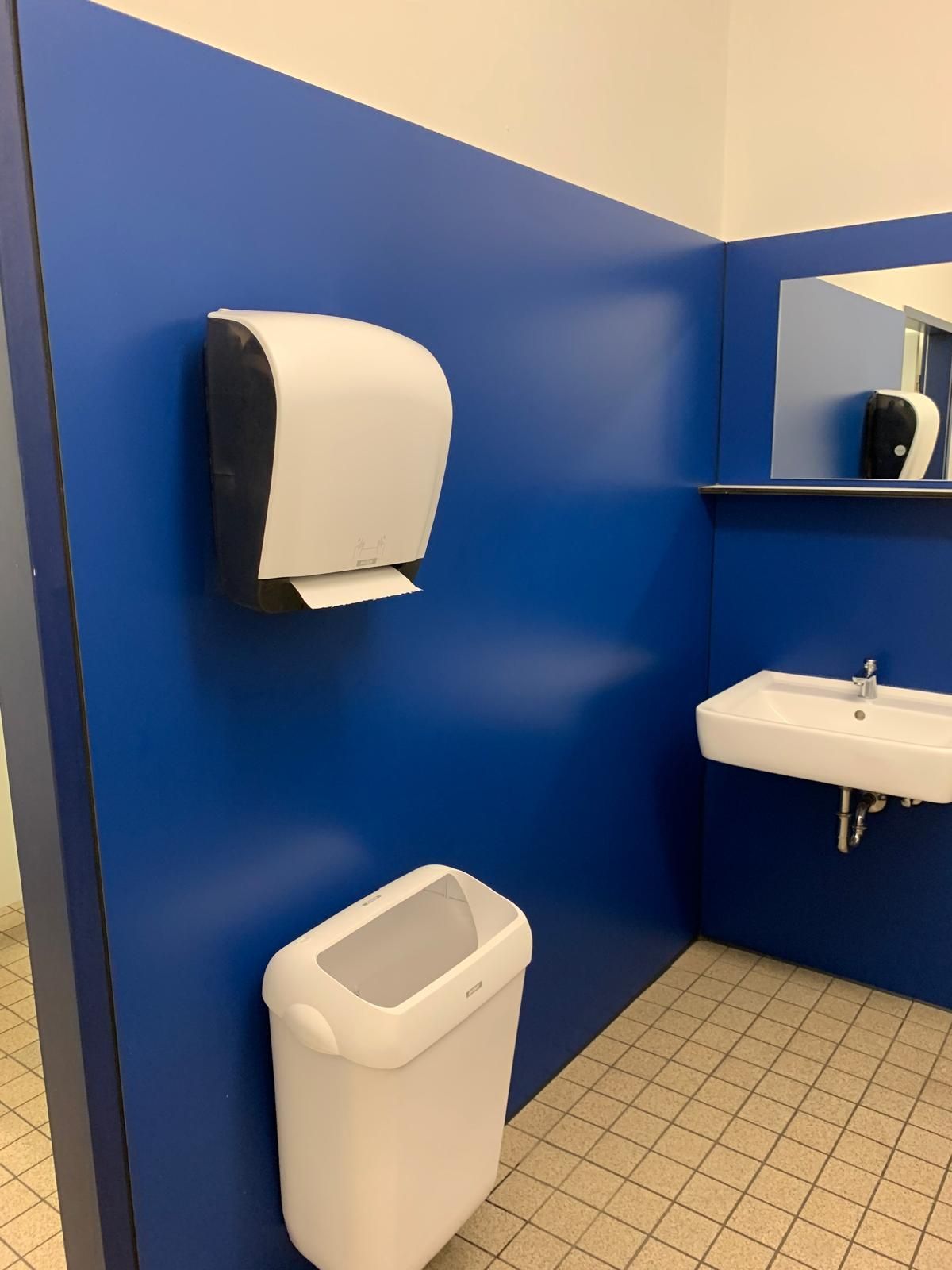 Ein Badezimmer mit blauen Wänden und einem weißen Mülleimer