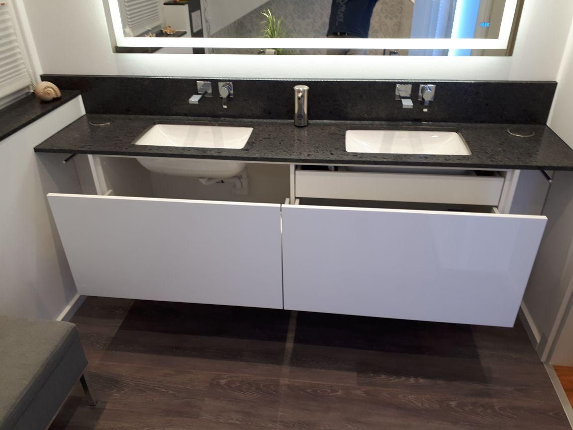 Ein Badezimmerschrank mit zwei Waschbecken und einem Spiegel