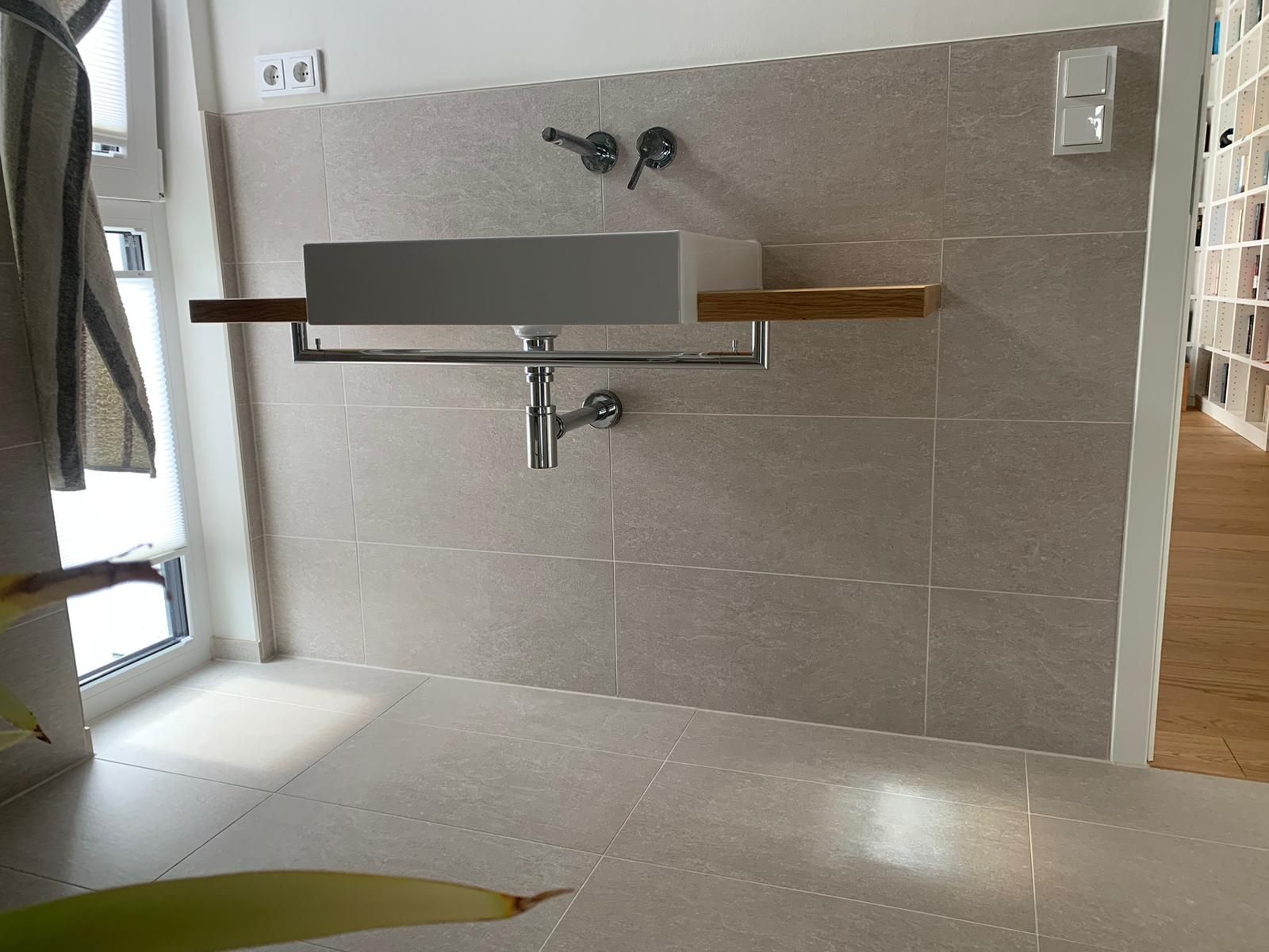 Ein Badezimmer mit einem Waschbecken und einem Regal an der Wand.