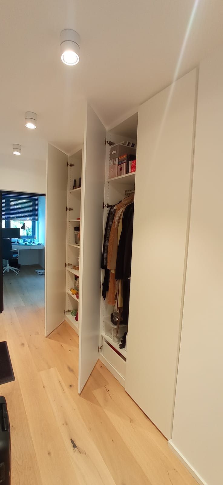 Ein Flur mit einem Schrank voller Kleidung und Schuhe.