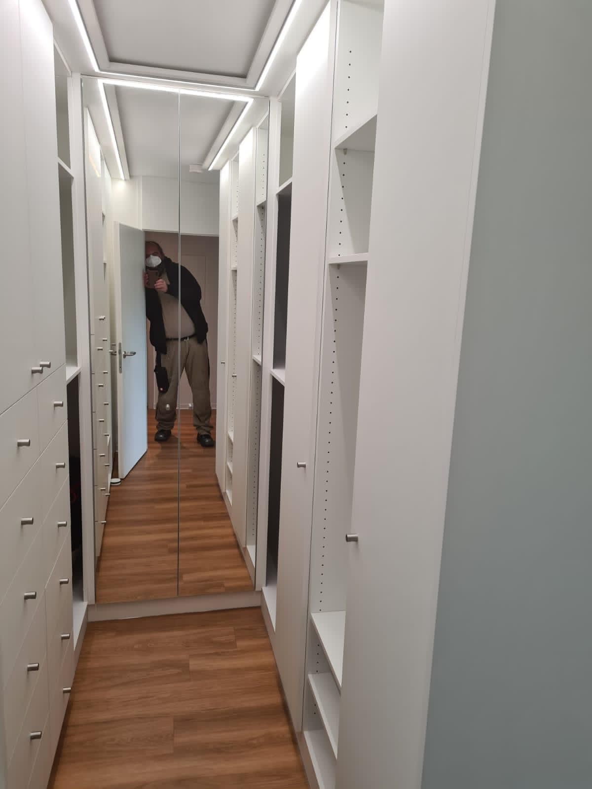 Ein Mann macht ein Foto von sich in einem begehbaren Kleiderschrank.