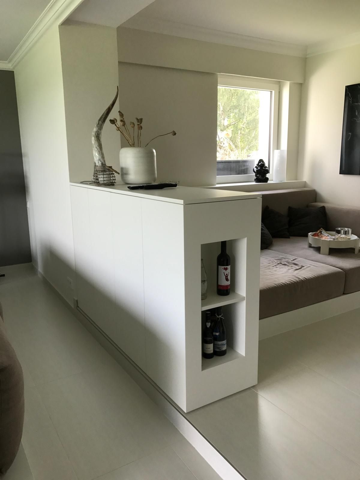 Ein Wohnzimmer mit einer Couch und einem Regal mit Weinflaschen darauf.