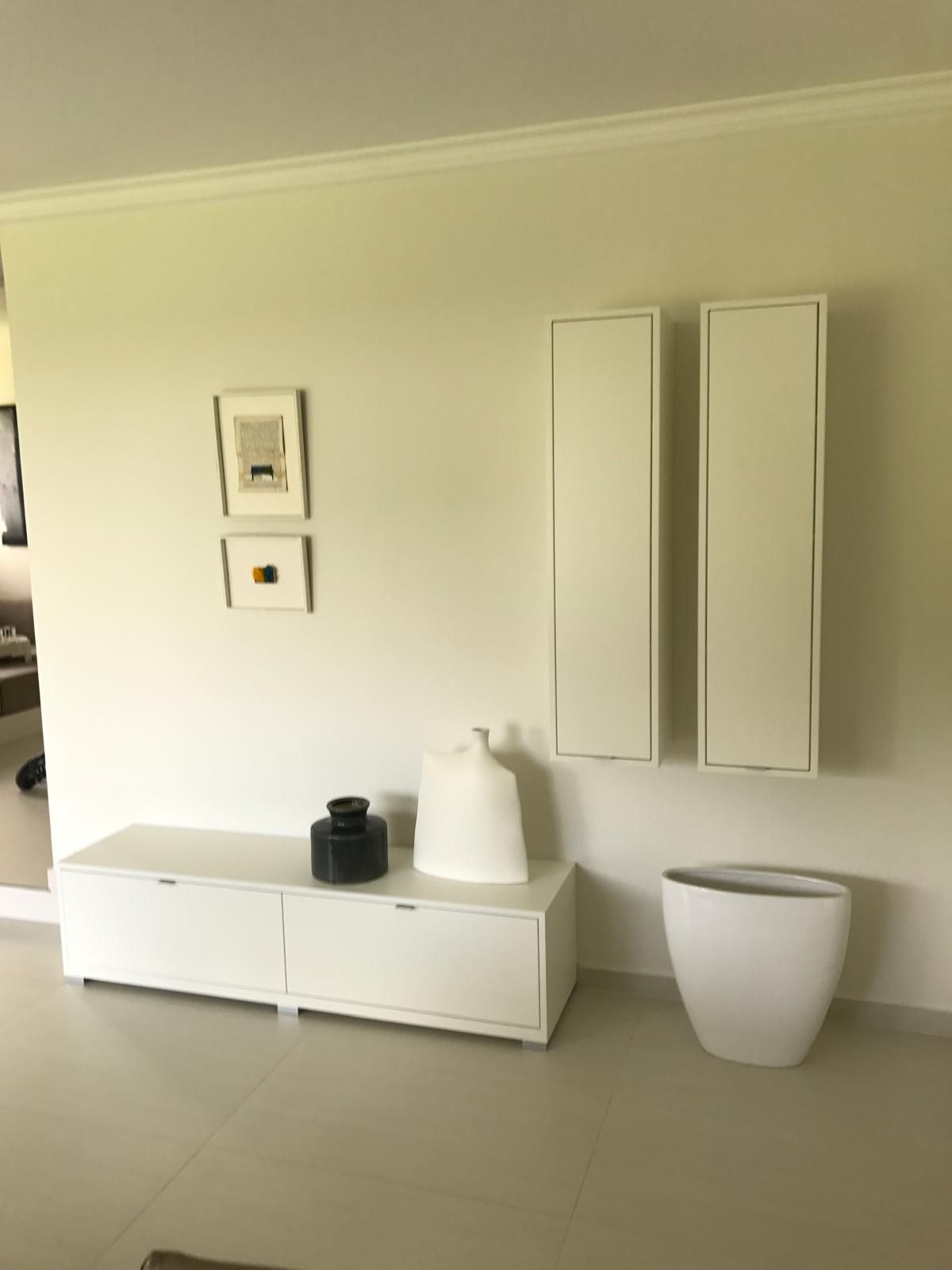 Ein Wohnzimmer mit einem weißen Regal und Vasen darauf